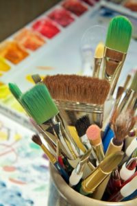 Tools of the artist including brushes and paint ready to be used.