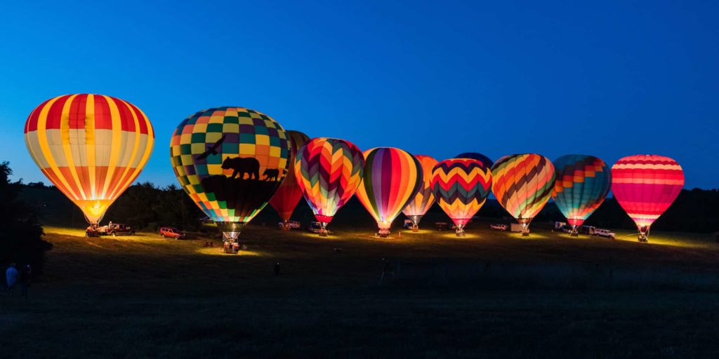 Hot Air Balloons at dusk with their fires burning to create a glow. 