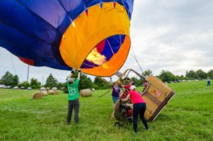 Blue and yellow hot air balloon being filled with hot air and made ready to float.