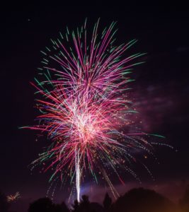 Red, green, and white fireworks in a dark sky.
