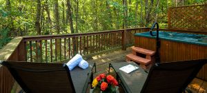 hot ub and lounge chairs on the deck of a cabin with a view of the forest