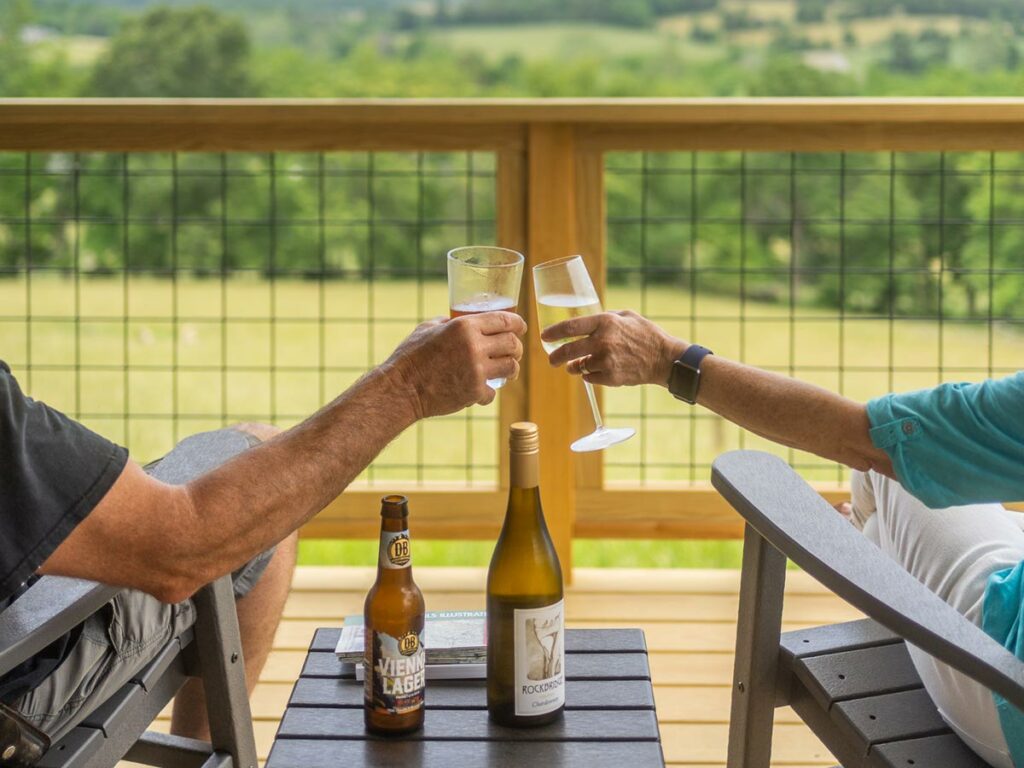 A couple sharing a glass of wine on our cabin porch, which is the perfect place to unwind while enjoying the best Blue Ridge Parkway fall colors