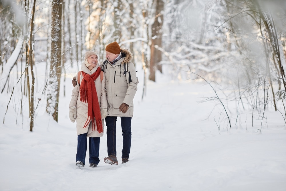 Couple walking in the snowy woods during their romantic getaways in Virginia